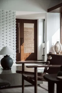 A modern lobby with concrete flooring, wooden furniture, and glass doors.