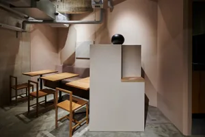 A minimalist restaurant interior with wooden furniture and concrete walls.