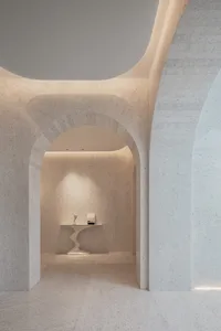 A minimalist marble lobby with arched doorways and curved table.