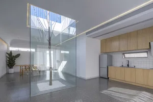 Modern minimalist kitchen with glass walls and wooden cabinets.