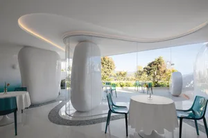 A modern restaurant interior with white tables and green chairs.
