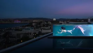A modern swimming pool with glass walls overlooking a cityscape.