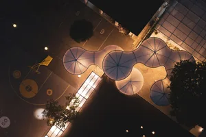 Aeriel view of a modern urban design featuring metal, glass, and concrete elements at night.