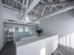 Modern minimalist bedroom featuring concrete floor and wooden ceiling beams.