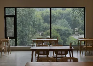 A minimalistic restaurant interior with wooden tables and chairs.
