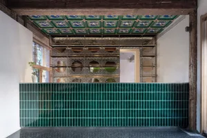 Modern bar interior with green tiled countertop and metallic shelving units.