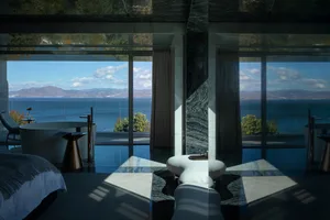 A modern bedroom featuring marble and glass materials with a stunning sea view.