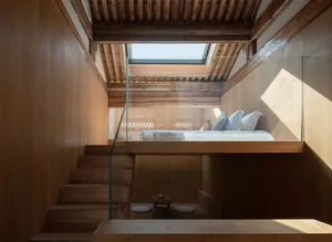 A modern bedroom featuring wooden elements, with a lofted bed and glass railing.