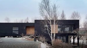 A contemporary house with a black metal exterior, featuring large glass windows and a minimalist design.
