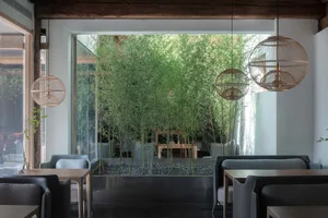 A modern coffee shop with wooden tables, glass walls, and metal accents.
