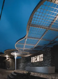 A modern entrance featuring a metallic grid and stone wall.