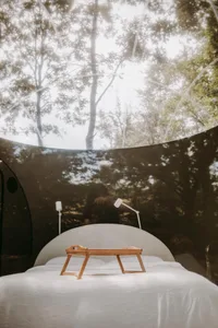 A modern bedroom featuring glass walls and a bed with white sheets.
