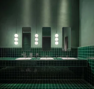 A modern restroom with green tiles and white sinks.