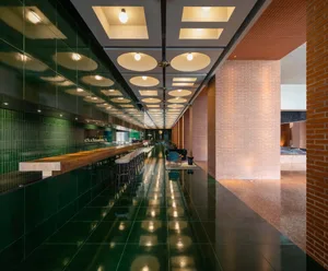 Modern hotel bar with glass wall and brick accents.