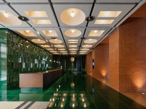 A modern industrial office space featuring tiled floors, brick walls, and glass elements.