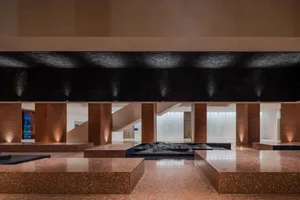 An elegant modern lobby with concrete columns and flooring, illuminated by soft lighting.