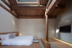 A contemporary bedroom featuring concrete walls, wooden floor and furniture, and a minimalist design.