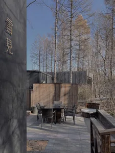 Modern outdoor patio area with wooden accents, glass panels, and stone flooring.