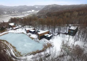 Modern, prefabricated houses surrounded by snowy, wooded terrain.