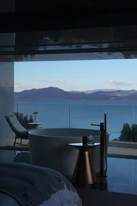 A modern residential bathroom featuring a glass tub overlooking a stunning mountain and sea view.