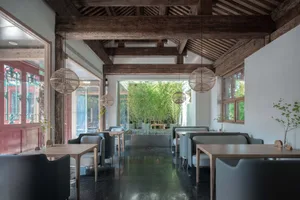 Modern restaurant interior with concrete flooring and bamboo plants.