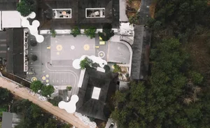Aerial view of a modern school ground plan with concrete and asphalt surfaces and artificial trees.