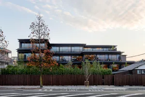 A modern building with a glass exterior, featuring multiple floors and a set of trees in front of it.