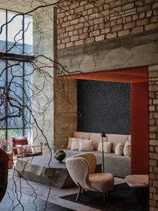 A modern living room with exposed concrete walls, a large sofa, and minimalist furniture.