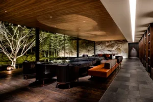 Modern hotel suite with contemporary interior design, featuring wooden furnishings, concrete accents, and a glass wall.