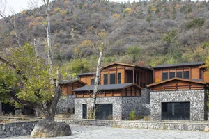 Modern residential houses with rock walls and wooden accents nestled in a valley.