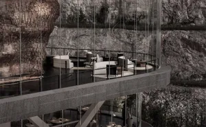 A modern indoor space featuring glass walls overlooking a rocky landscape.