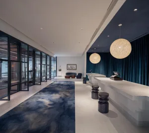 Modern lobby with tiled flooring, concrete seating, and stools