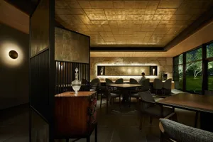 Modern restaurant interior with wooden tables, stone accents, and metal decor.