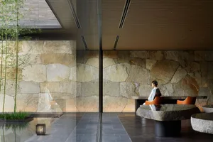 A serene spa interior features stone walls and bamboo plants, creating a peaceful ambiance.