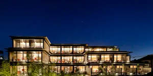 A modern building with a glass exterior illuminated at night, with a clear sky above.