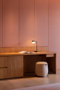 A modern desk space with a wood finish, featuring an open book and a table lamp.