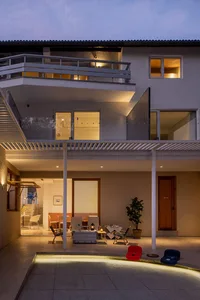 Modern house exterior with concrete finishes, illuminated by warm lights at dusk.