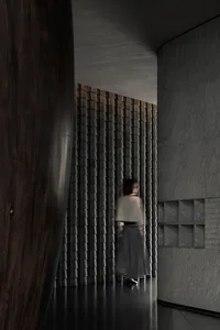 A person walking past a textured brick wall in a modern interior space