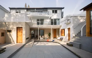 A modern residential outdoor space featuring concrete, glass, and wood materials.