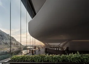 A modern restaurant features a glass ceiling and large terrace overlooking a landscape.