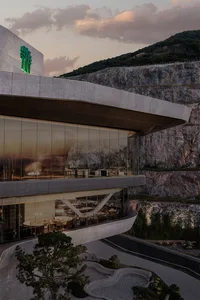 Modern restaurant interior featuring large glass walls and concrete elements.