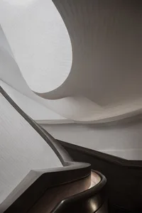 A modern staircase with wooden railings and a curved design.