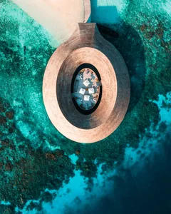 A circular, concrete structure surrounded by turquoise waters, providing a scenic ocean view.