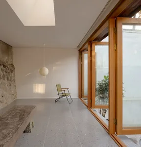A minimalist residential space featuring a window, chair, and bench with light-colored flooring and wooden elements.