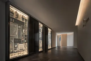 A minimalist corridor featuring glass walls and metallic elements.