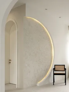 A minimalist interior design featuring a textured cement wall with a circular cut-out and embedded lighting, complemented by 