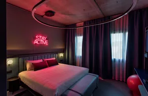 A modern bedroom featuring neon lighting, fabric headboard, and glass window.