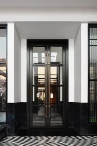 Modern black glass double doors with brass handles and marble accents
