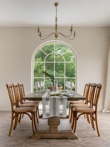 A modern dining room with a wooden table, glass vases, and fabric chairs.