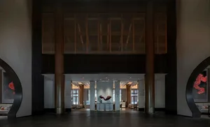 Modern hotel lobby featuring concrete columns and floors, with a large sculpture in the center.